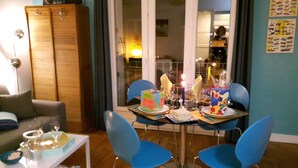 A dining area with a table set for four, blue chairs, and a cabinet in the background. - Apartment 40 m2, very comfortable, south facing, Le Tréport, full center and beach (Le Tréport)