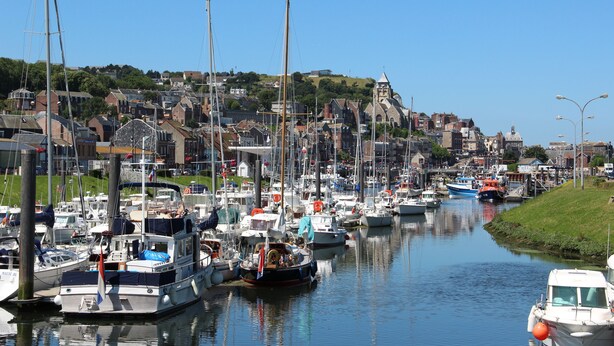 A marina with various boats docked along a calm waterway, surrounded by residential buildings and a hill with a church steeple in the background. - Apartment 40 m2, very comfortable, south facing, Le Tréport, full center and beach (Le Tréport)