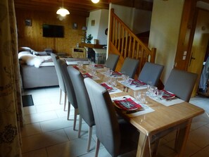 A dining area with a long wooden table set for a meal, surrounded by chairs. - Independent chalet on 2 levels with parking and WIFI classified 3 stars (Arâches-La-Frasse)