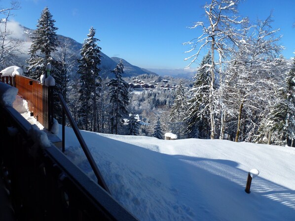 Eine verschneite Berglandschaft mit einem Holzzaun und schneebedeckten Bäumen.