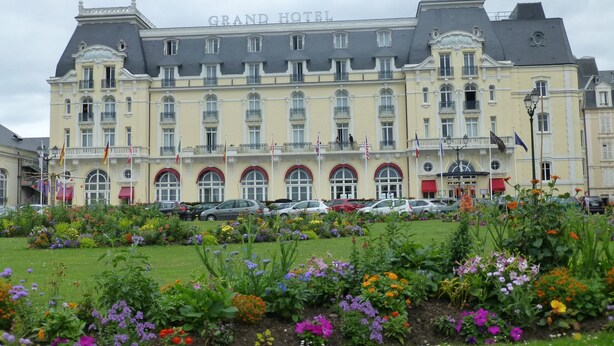 Un grand bâtiment d’hôtel doté de nombreux balcons et d’un jardin à l’avant.