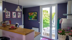 Une cuisine dotée d’un plan de travail en bois, de luminaires suspendus et donnant sur un patio extérieur.