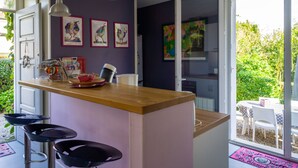 Une cuisine moderne avec un îlot central en bois, des tabourets de bar et un coin repas comprenant une table et des chaises.