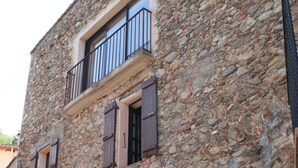 Un bâtiment en pierre doté d’un balcon et d’une entrée en arc de cercle.