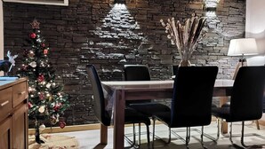 Een eetruimte met een stenen muur, een kerstboom en een tafel met stoelen.
