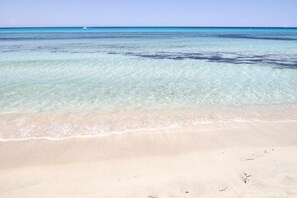 A beach with clear turquoise water and a sandy shore.