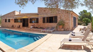 Une villa en pierre dotée d’une piscine, d’un espace salon extérieur et d’un patio couvert.