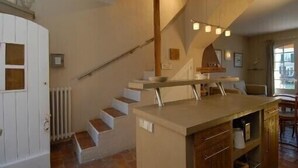 A modern kitchen with a central island, a staircase, and a dining area with a view. - Fisherman's house in Port-Grimaud (Grimaud)
