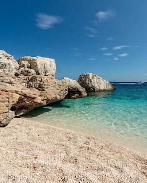 Costa rocosa con agua turquesa cristalina y una playa de guijarros.
