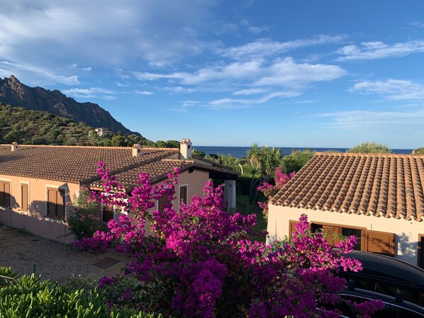 Una villa costera con techos de tejas de barro, un jardín con buganvillas y vistas al mar y a las montañas.