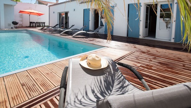 A poolside area with a wooden deck, lounge chairs, and a table with an umbrella. - Former fisherman's house with pool in the heart of Old Cotinière (Saint-Pierre-D'oléron)