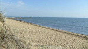 A sandy beach with a rocky breakwater and a lighthouse in the distance. - Former fisherman's house with pool in the heart of Old Cotinière (Saint-Pierre-D'oléron)