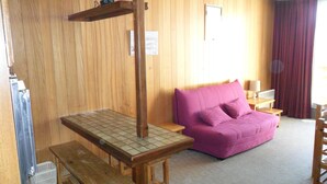 A room with wooden walls, a purple sofa, a wooden table, and a bench. - Holiday Apartment (Orcières)