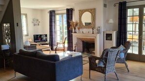Ein Wohnzimmer mit einer Couch, einem Korbsessel, einem Kamin und einem Fernseher.