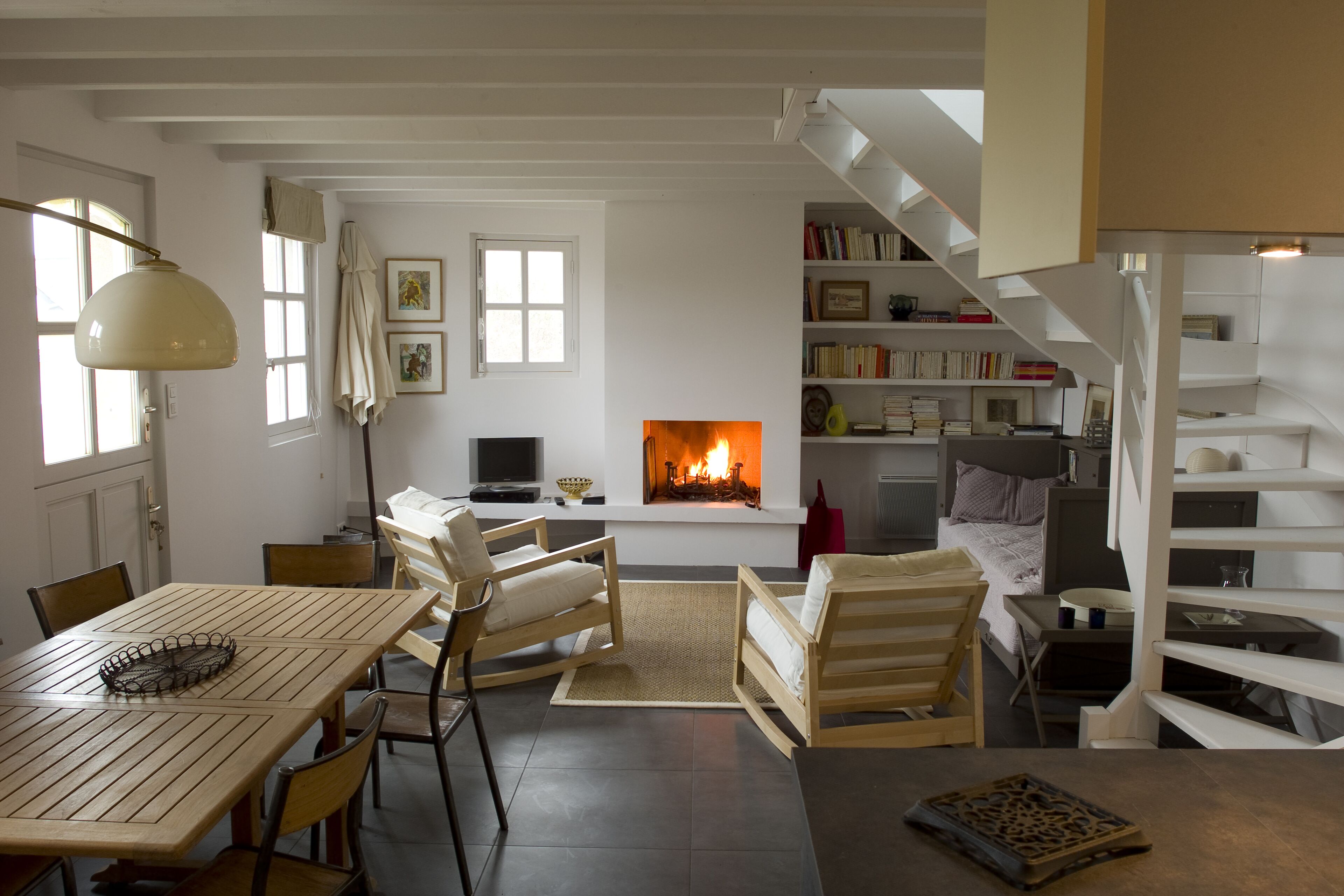 A cozy living room with a fireplace, wooden furniture, and a staircase.
