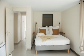 Um quarto com cama, mesas de cabeceira e uma janela.