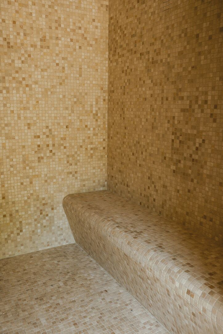 A corner of a room with a tiled wall and a curved bench.