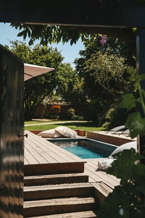 A wooden deck with a hot tub, surrounded by greenery and trees.