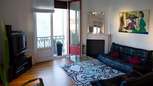 Un salon avec un canapé, un téléviseur, une cheminée et un tableau au mur.