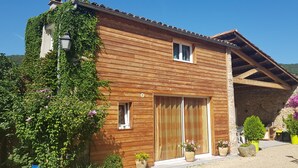 Une maison en bois avec une façade en pierre, de grandes portes en bois et une petite fenêtre.