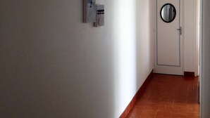 Un couloir avec une porte blanche, un miroir rond et trois œuvres d’art encadrées accrochées au mur.