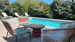 Ein Poolbereich mit Korbstühlen und einem runden Tisch.