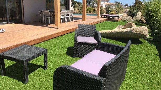 Eine Terrasse mit Gartenmöbeln, ein Holzdeck und ein Pool.