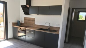 Eine moderne Küche mit Holzausziehtisch, schwarzen Schränken, einem eingebauten Ofen und einem Fenster mit Blick auf einen Balkon.