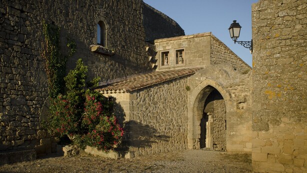 A stone building with an arched entrance, a window, and a street lamp. - Charming house in medieval village with pond view terrace, private parking (Miramas)
