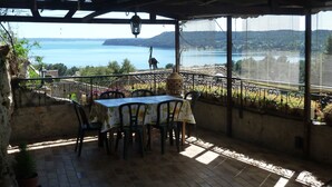 A covered patio with a table and chairs, overlooking a lake and hills. - Charming house in medieval village with pond view terrace, private parking (Miramas)