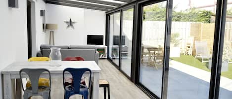A modern patio area with a dining table, chairs, and a sofa.
