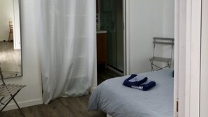 Une chambre à coucher comprenant un lit, un miroir, une armoire et un espace douche.