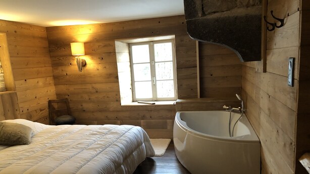 Un dormitorio de cabaña de madera con una cama, una ventana y una bañera.