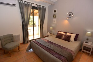Ein Schlafzimmer mit einem Bett, einem Sessel, einem Nachttisch und einer Wandleuchte.