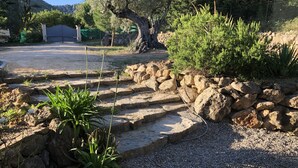 Un jardín con escalones de piedra, una terraza de madera y un camino de grava.