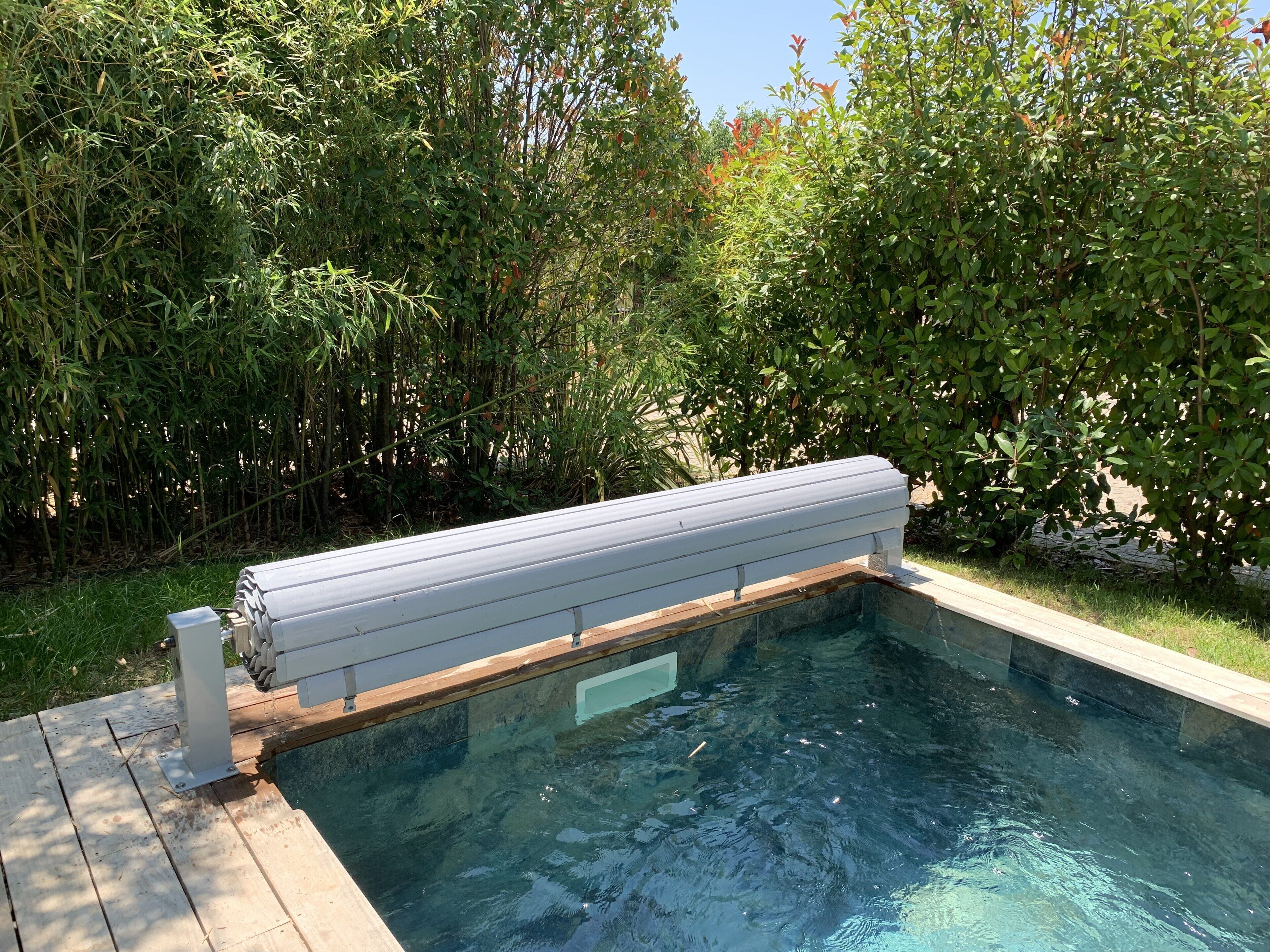 Una piscina con cubierta de madera y una barandilla de seguridad metálica.