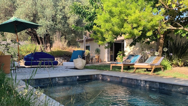 Piscina con sillones de descanso y un área de estar cubierta.