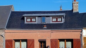 Een tweelaags gebouw van baksteen met een puntig dak, een klein dakraam en een schoorsteen.