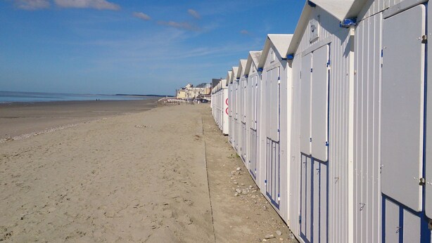 Een strand met een rij witte strandhutten langs de kust.