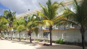 A beachfront hotel with multiple rooms, palm trees, and a sandy beach area.