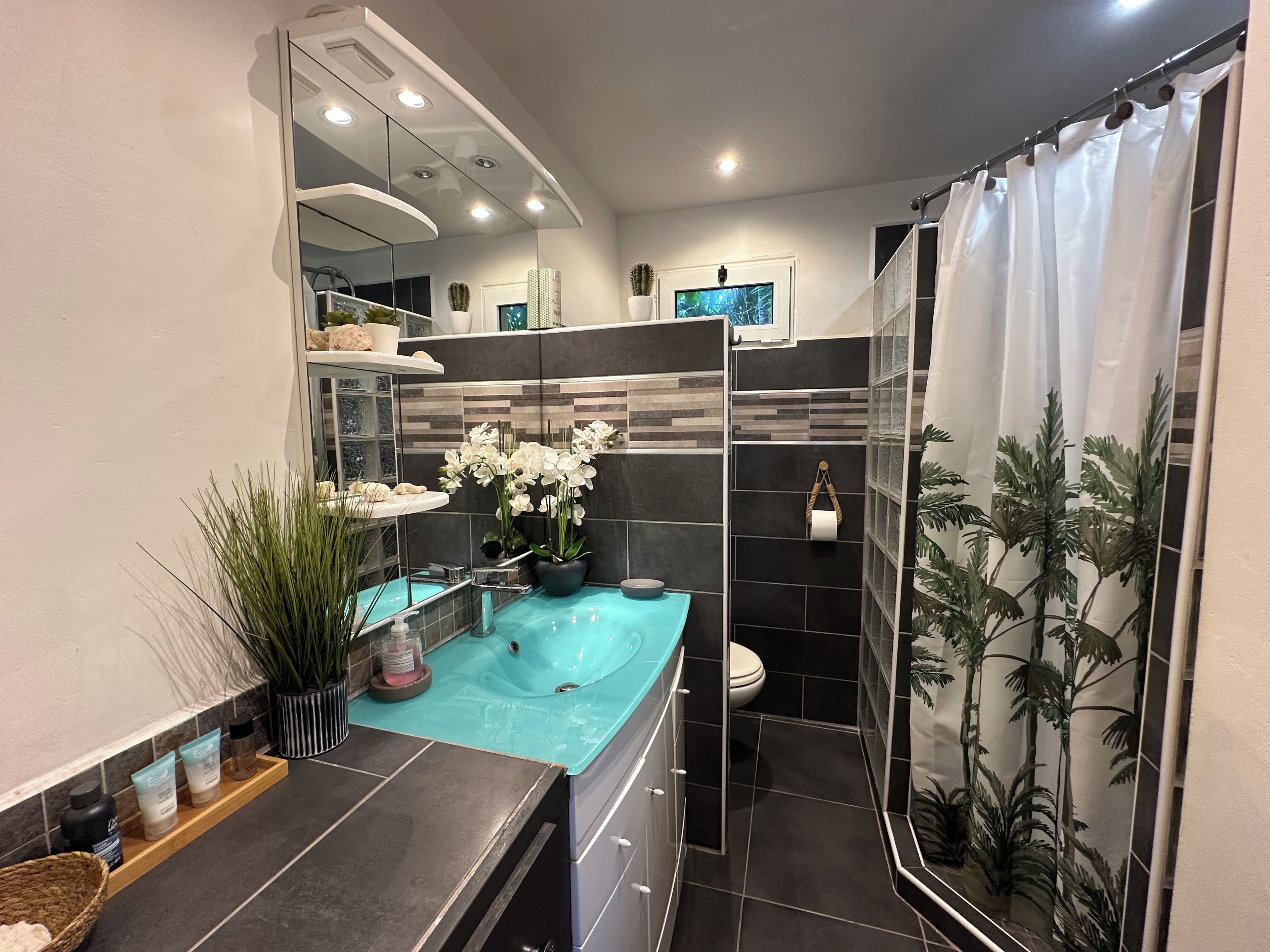 A modern bathroom with a large mirror, a bathtub, a toilet, and a shower area.