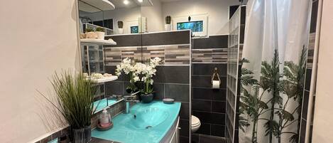 A modern bathroom with a large mirror, a bathtub, a toilet, and a shower area.