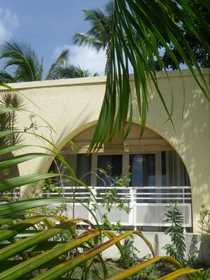 A building with a beige exterior, an arched window, and a balcony with a white railing.