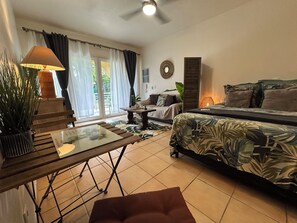 Une pièce comprenant un lit, un canapé, une table avec une lampe et une plante en pot.