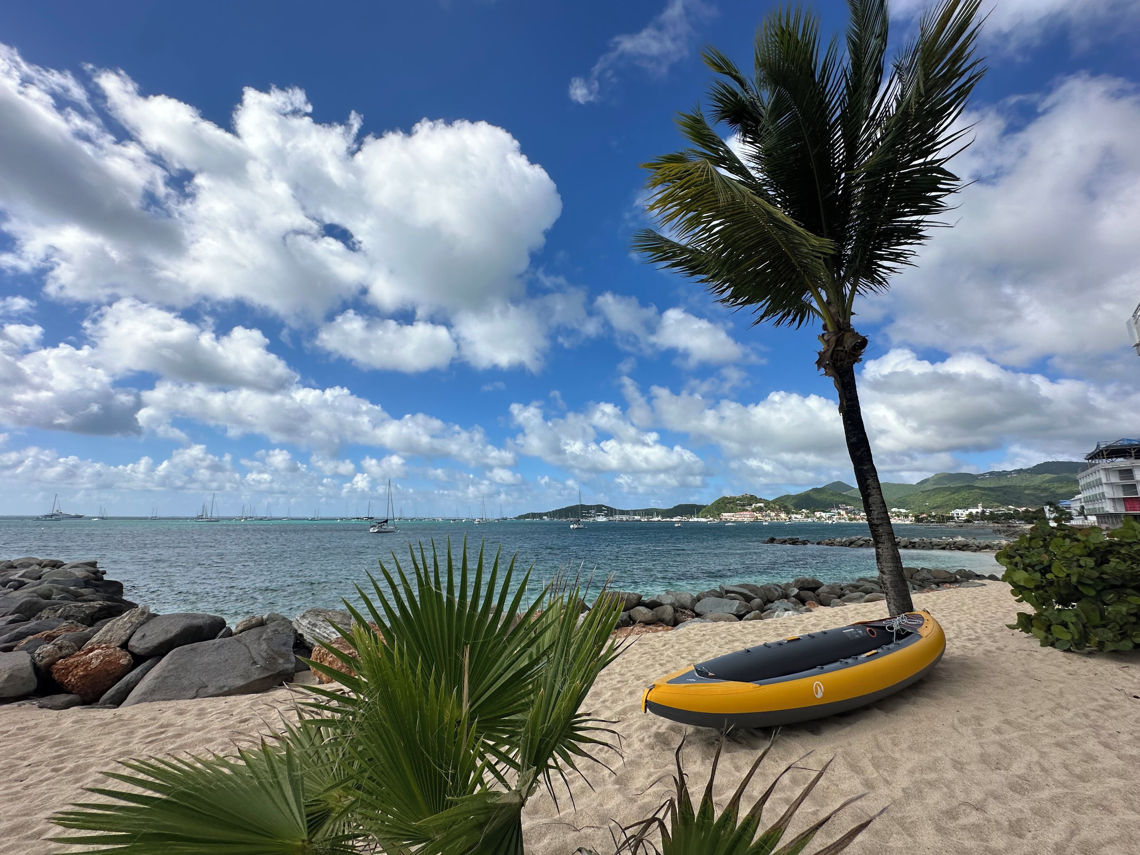 Ein Strand mit einem gelben Rettungsboot, Palmen und blauem Himmel.