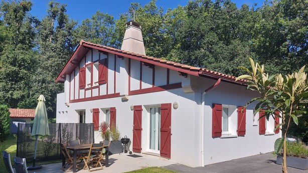 A two-story house with a red-tiled roof, white walls, and red shutters. There is a patio with outdoor furniture and a grill. - Bidart, pretty apartment for 4 people, close to beaches and center of Guéthary  (Bidart)
