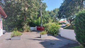 A parking area with a red gate, surrounded by greenery and a white fence. - Bidart, pretty apartment for 4 people, close to beaches and center of Guéthary  (Bidart)