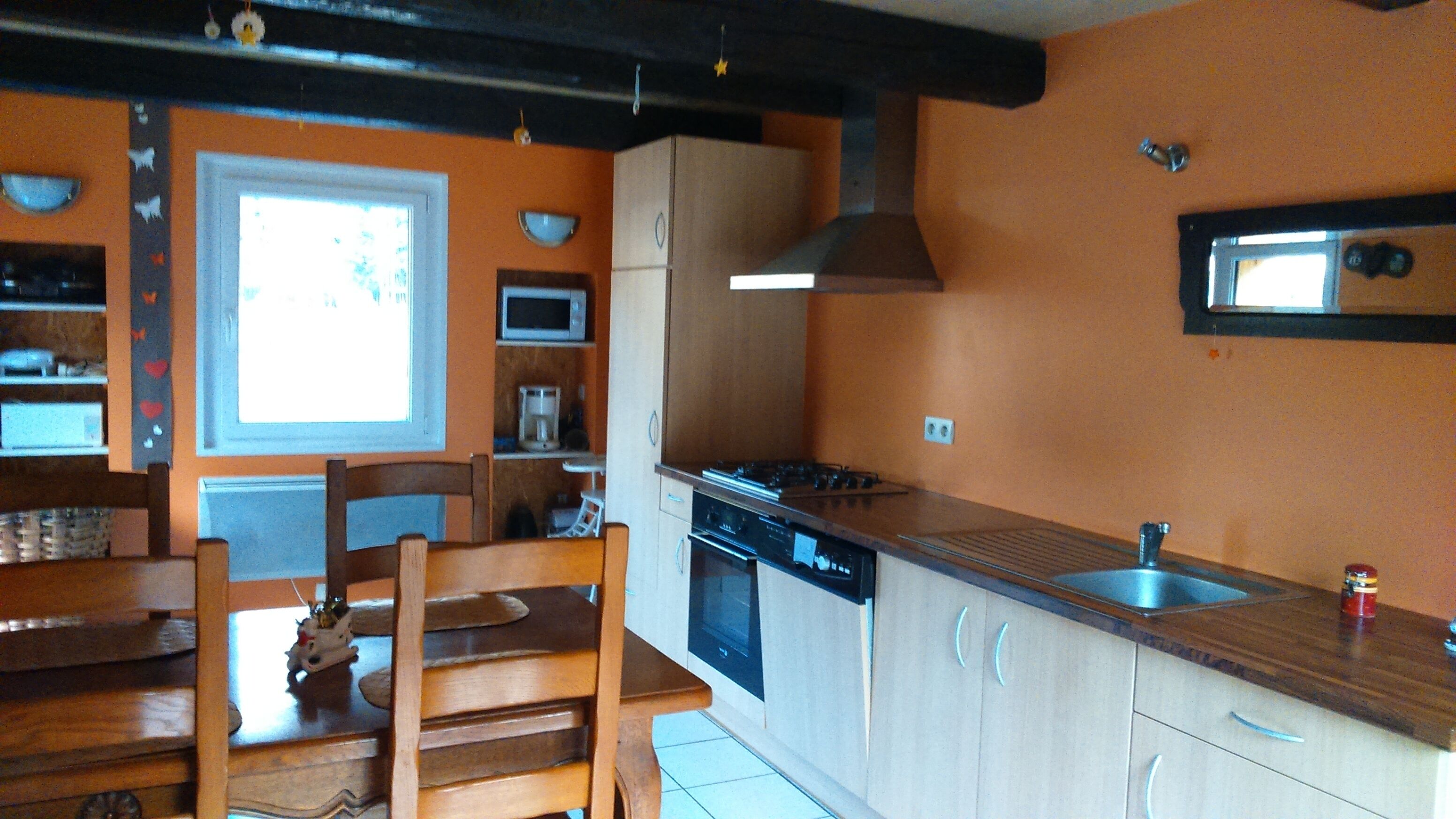 A kitchen with wooden cabinets, a stove, a microwave, and a window.