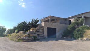 Un bâtiment moderne avec une façade en pierre, un espace extérieur couvert et un garage.