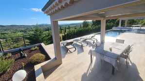 Un espace extérieur abrité comprenant une piscine, des chaises longues et une table.